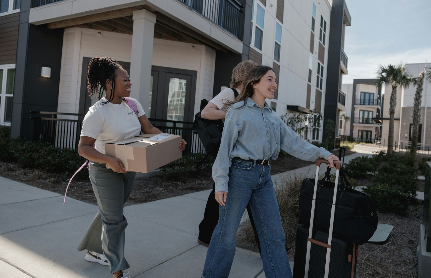 Two friends carrying boxes into their new apartment building