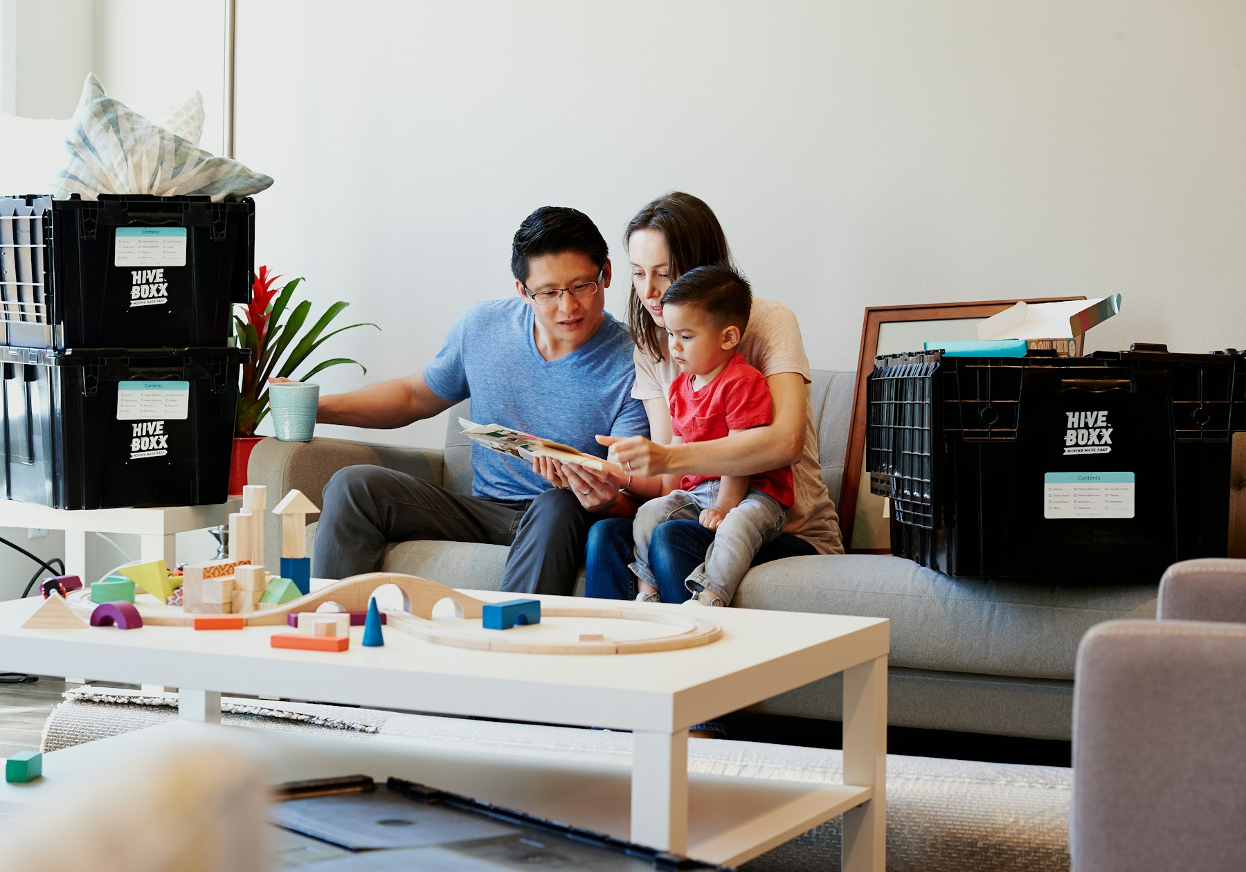 A family with their toddler on the couch of their new home, unpacking together